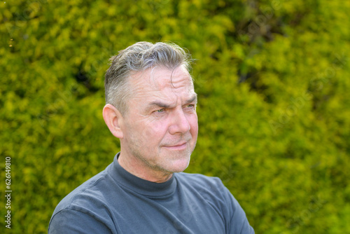 Portrait of a middle-aged man with gray hair standing in the garden