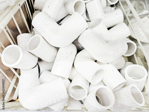 Close-up of Pile of Parts of plastic piping. Pile of white  PVC Pipe fittings at Storage piping parts plastic materials on warehouse.