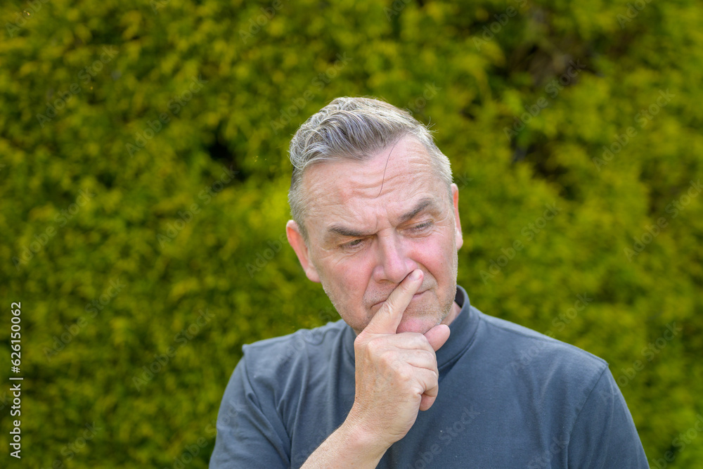 Portrait of a middle-aged man with gray hair standing in the garden Portrait of a middle-aged man with gray hair standing in the garden