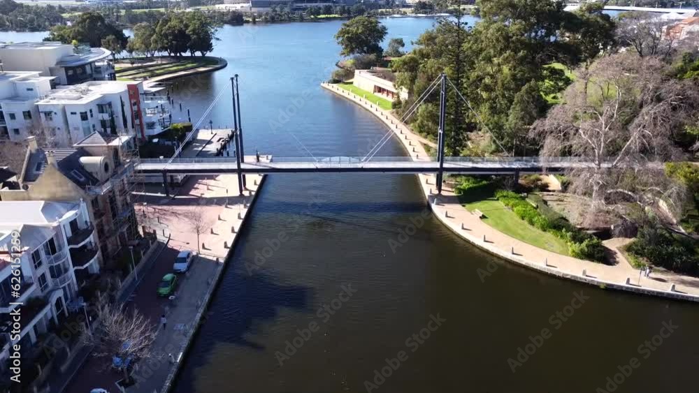 Drone Aerial View zooming backwards over people walking along Suspension pedestrian bridge in Claisebrook Cove, East Perth and Swan River Drone Aerial View zooming backwards over people walking along Suspension pedestrian bridge in Claisebrook Cove, East Perth and Swan River