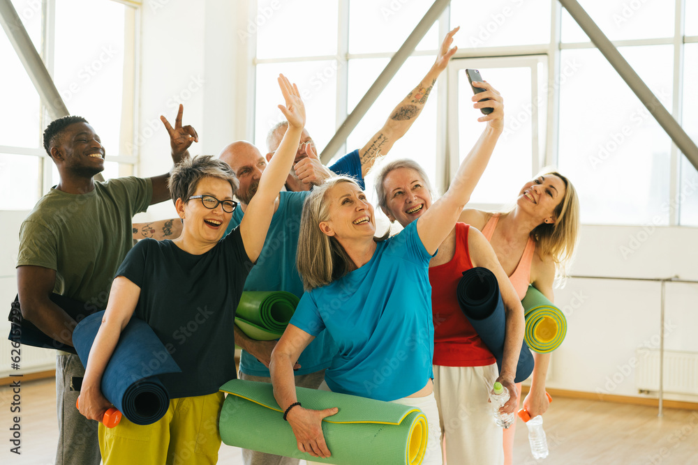 Fototapeta premium Pensioners athletes taking selfies on smartphone in gym