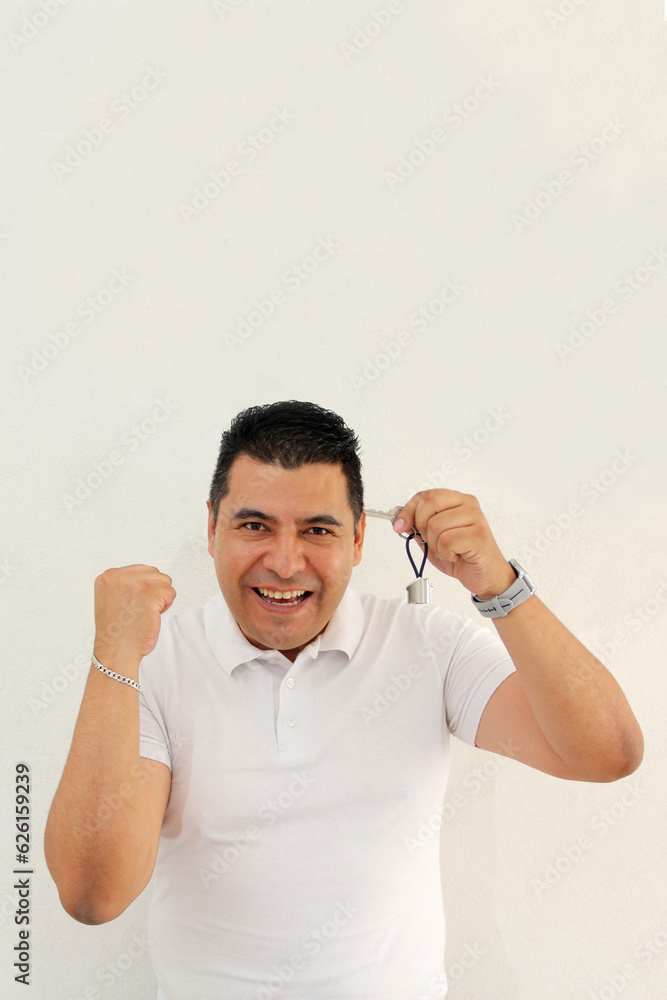 Excited and successful 40-year-old dark-haired Latino man shows the keys of his new house that he bought with a real estate agency Excited and successful 40-year-old dark-haired Latino man shows the keys of his new house that he bought with a real estate agency