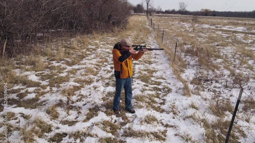 Hunter with sniper rifle aiming looking for targets, close up aerial view Hunter with sniper rifle aiming looking for targets, close up aerial view
