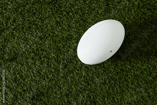 White rugby ball over grass with copy space, in slow motion