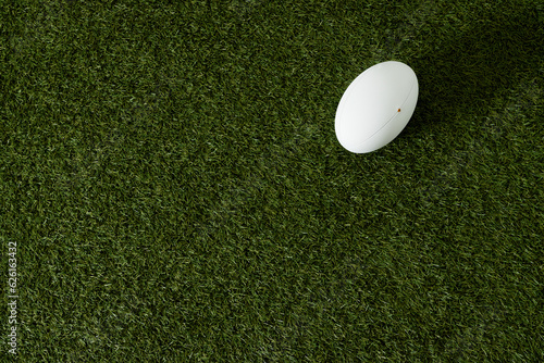 White rugby ball over grass with copy space, in slow motion
