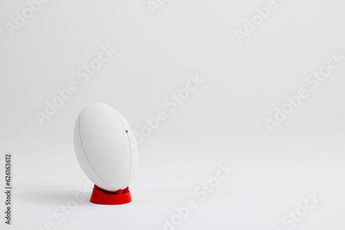 White rugby ball on red stand with copy space on white background