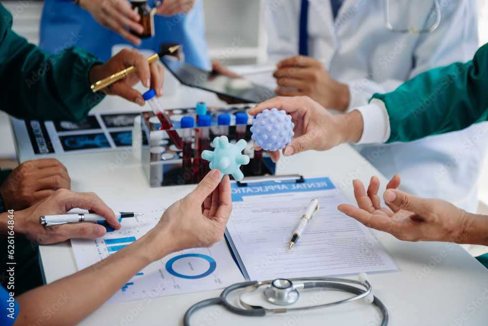 Obraz premium Medical team having a meeting with doctors in white lab coats and surgical scrubs seated at a table discussing a patients working online using computers in the medical industry