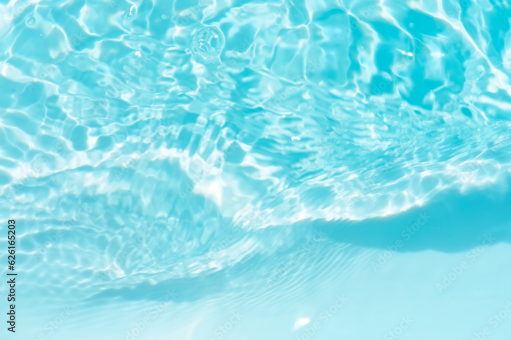 Obraz premium Blue water with ripples on the surface. Defocus blurred transparent blue colored clear calm water surface texture with splashes and bubbles. Water waves with shining pattern texture background.