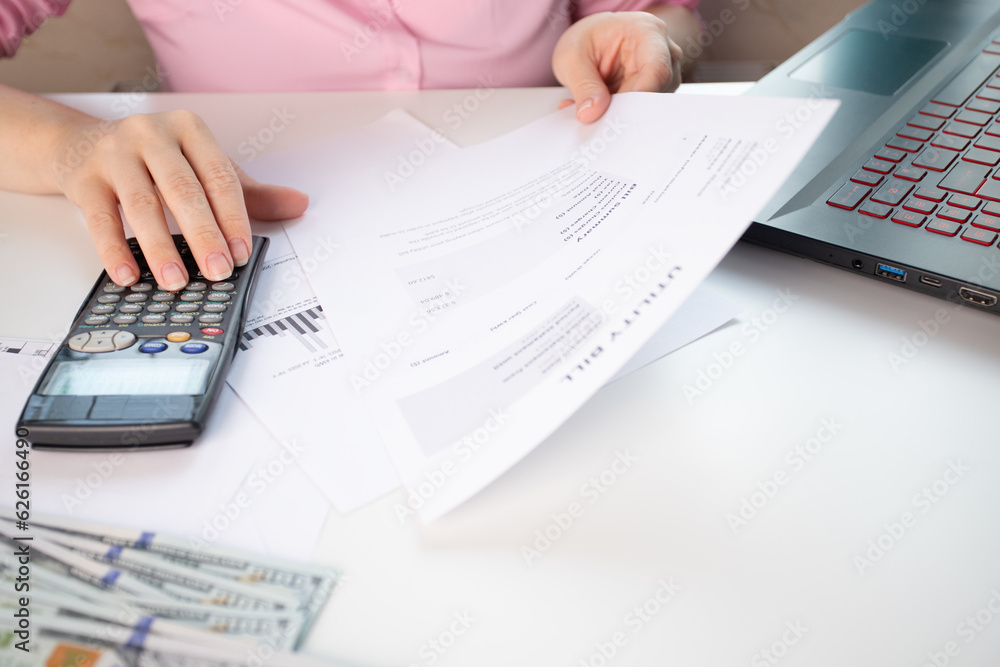 Receipt for utility services, Rising energy costs reflected in the bill, Invoice for electricity and gas services, woman at home counting utility bills on a calculator Receipt for utility services, Rising energy costs reflected in the bill, Invoice for electricity and gas services, woman at home counting utility bills on a calculator