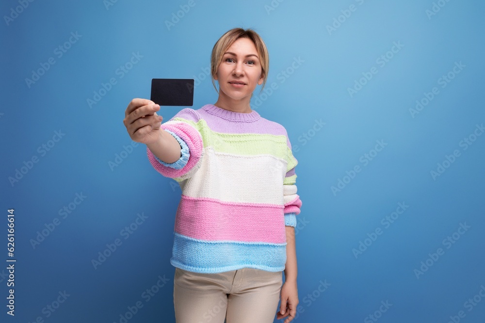 attractive blond woman in casual look demonstrating credit card mockup on blue background attractive blond woman in casual look demonstrating credit card mockup on blue background