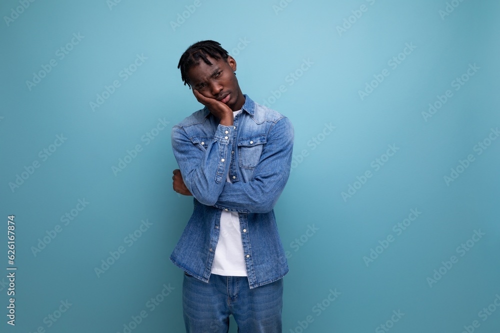 Fototapeta premium brunette man with curly hair in a denim jacket on a blue background