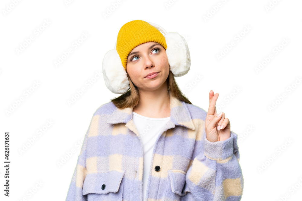Young blonde woman wearing winter muffs over isolated chroma key background with fingers crossing and wishing the best