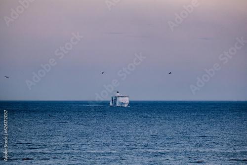 Passenger pax cargo car roro ro-ro ferry boat vessel cruiseship cruise ship liner at sea with sky and coastline