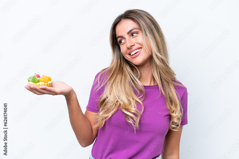 Young pretty Uruguayan woman holding a tartlet isolated on white background with happy expression Young pretty Uruguayan woman holding a tartlet isolated on white background with happy expression