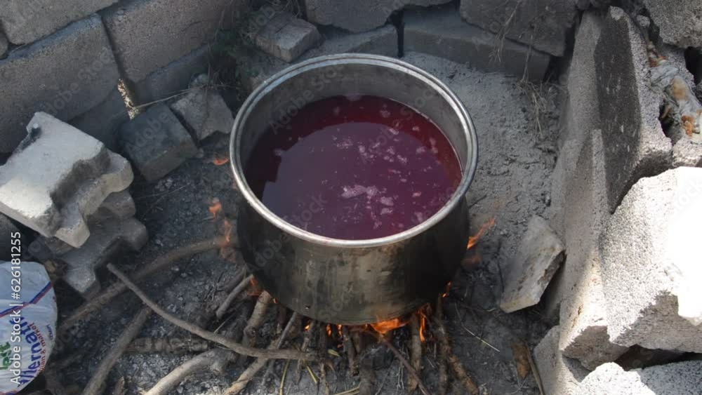 boiling pomegranate juice in a wood-fired black cauldron boiling pomegranate juice in a wood-fired black cauldron