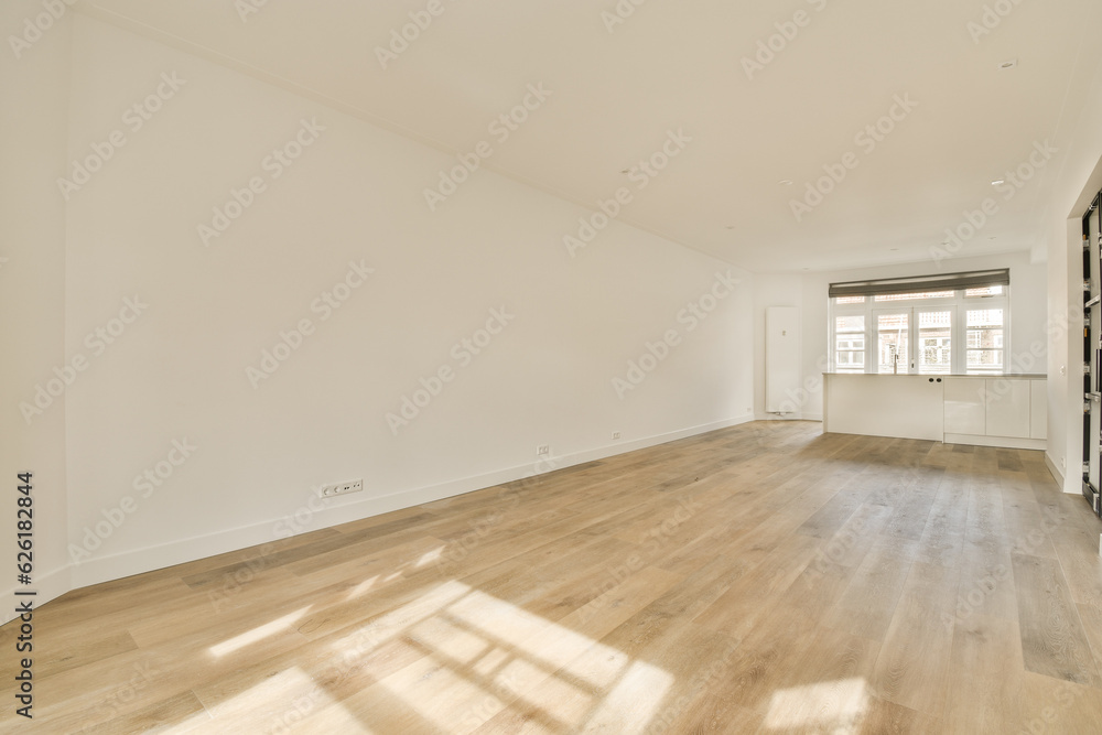 Fototapeta premium an empty living room with wood flooring and white walls on either side of the room, there is a large window in the