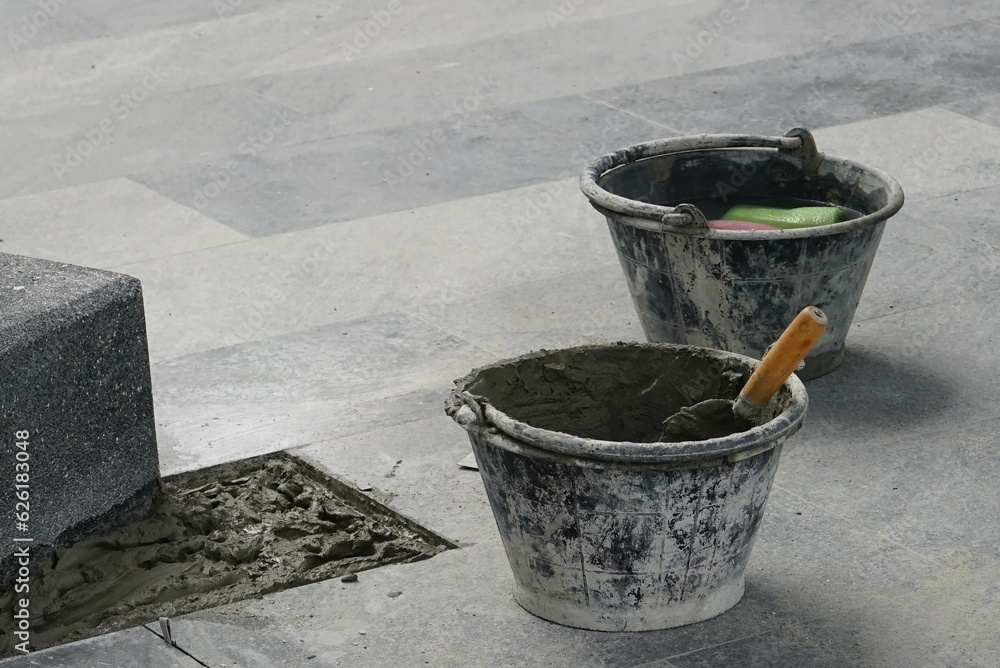 A construction trowel and cement bucket on the floor to preparing work. A construction trowel and cement bucket on the floor to preparing work.
