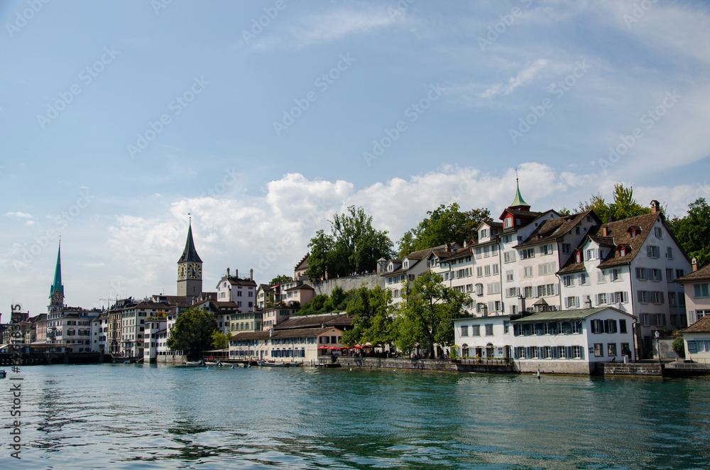 View of some typical Swiss houses and St. Peter and Fraumünster churches at the edge of the Limmat, the river in Zurich