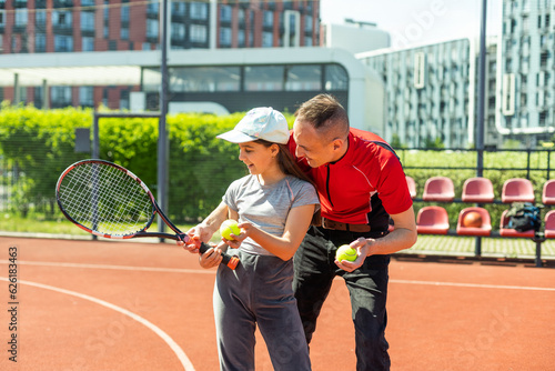 Father is a tennis coach for his daughter. Female child is playing in tandem with her daddy in doubles tennis © Angelov