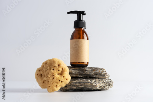 Mock up brown glass bottle and sea natural sponge on a stone podium