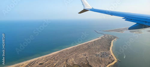 A passanger plane wing image with a land bellow
