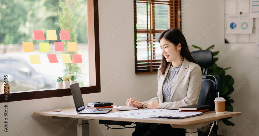 Beautiful woman using laptop and tablet while sitting at her working place. Concentrated at work.. Beautiful woman using laptop and tablet while sitting at her working place. Concentrated at work..