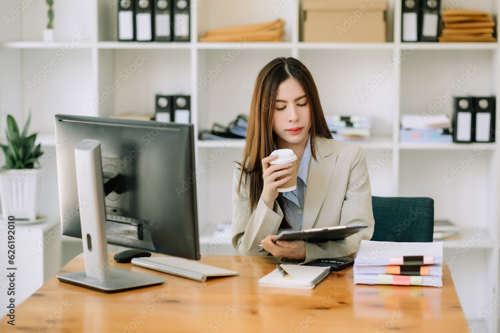 Asian woman using laptop and tablet while sitting at her working place. Concentrated at work.. Asian woman using laptop and tablet while sitting at her working place. Concentrated at work..
