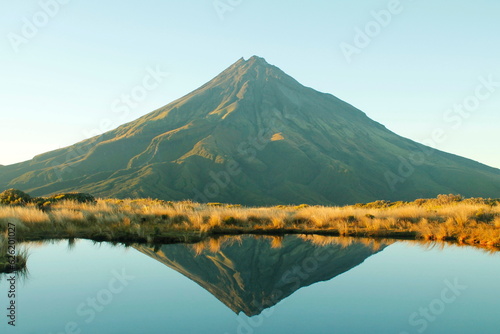 Reflection of a triangle shaped Taranaki mountain in sunrise