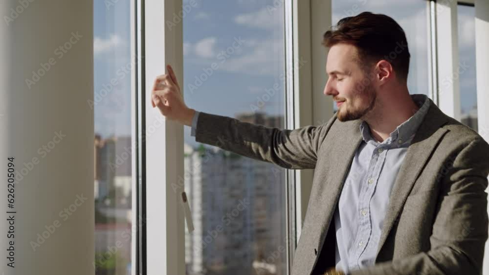 Success man in good suit stay in office and look at window and after at watch. Concept of waiting for something or someone, a big money, success, when dreams comes true. He smile and are happy Success man in good suit stay in office and look at window and after at watch. Concept of waiting for something or someone, a big money, success, when dreams comes true. He smile and are happy