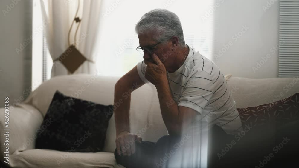 Senior Man Experiencing Frustration and Preoccupation, Alone at Home in Candid Scene, sitting on couch in quiet contemplation Senior Man Experiencing Frustration and Preoccupation, Alone at Home in Candid Scene, sitting on couch in quiet contemplation