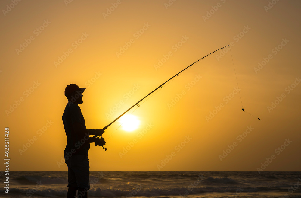 Silhouette of a fisherman at sunset 