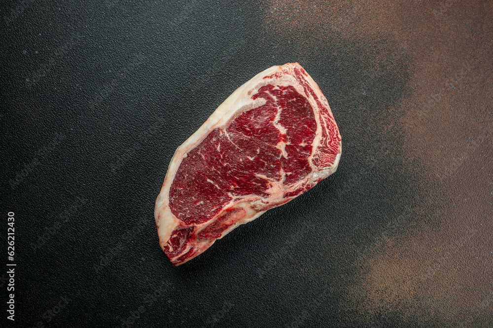 Raw New York steak on a dark background. banner, menu, recipe place for text, top view