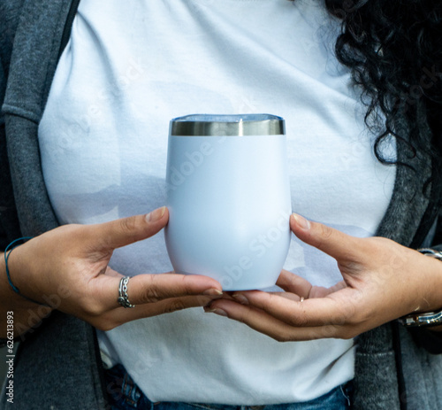 A woman with a white wine tumbler mockup, impressively showcasing your brand's charm and elegance