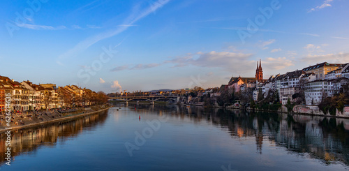 Panoramic view of the Basel embankment along the Rhine at sunset. The silhouettes of the historic buildings of the old city are reflected in the calm surface of the water © tatiana