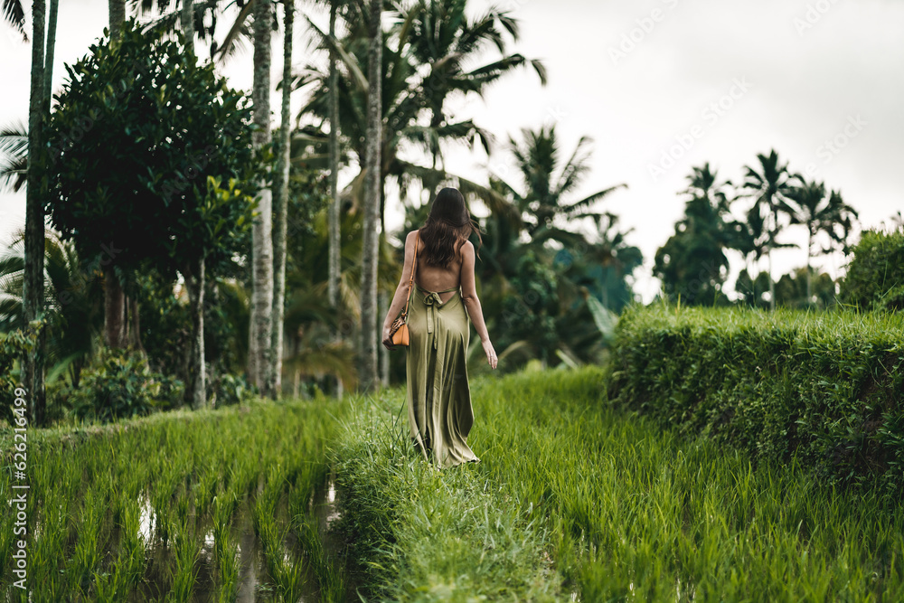 Stylish lady in green sexy dress on footpath rice terrace. Young elegant lady admiring evergreen balinese nature