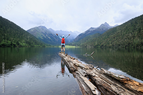 Woman traveller open arms to foggy high altitude mountains photo