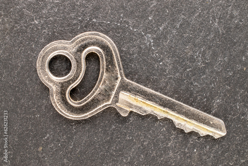 One key to a door lock on a slate stone, close-up, top view. © Oleksandr