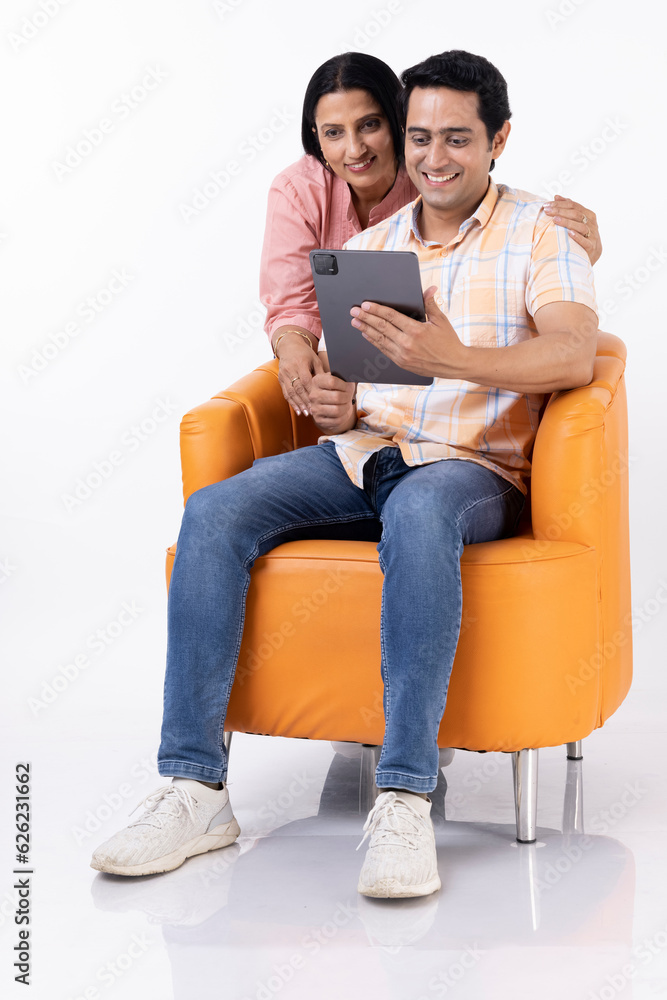 Mother and son shopping online together on tablet, while relaxing at home.