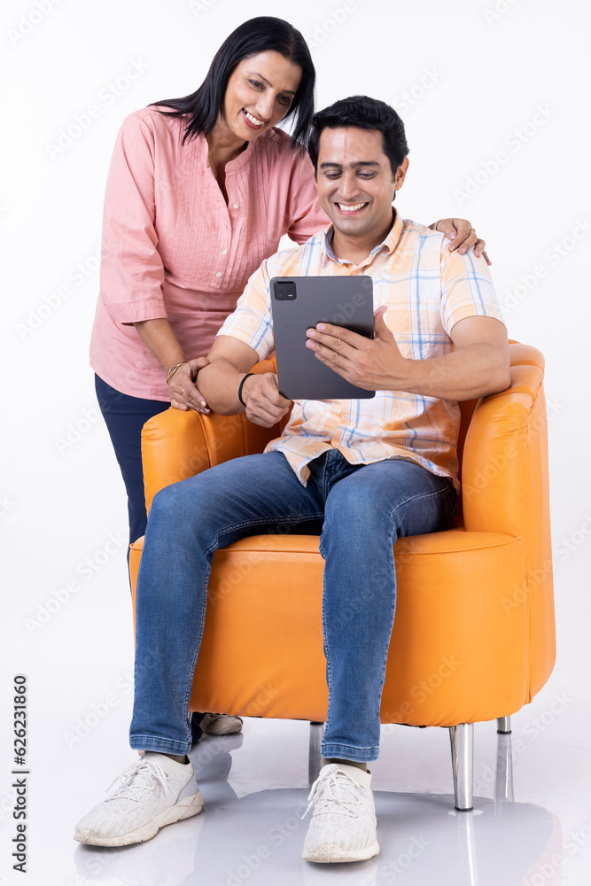 Mother and son shopping online together on tablet, while relaxing at home. Mother and son shopping online together on tablet, while relaxing at home.