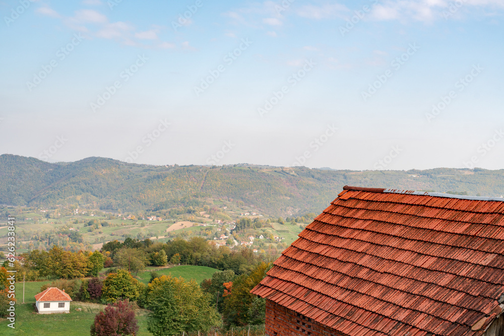 Red tiled roof of a house in autumn mountains