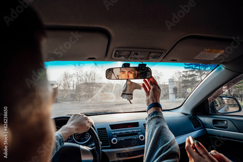 The young adventurer ensures a safe journey by adjusting the car's rearview mirror, covering the topic of travel and exploration