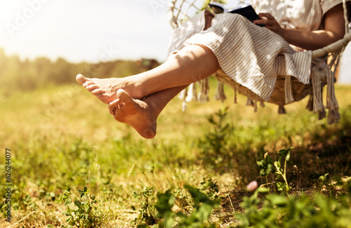 Fototapeta Naklejka Na Ścianę i Meble -  Women legs, barefoot girl sitting on swings in nature, outdoor on summer holiday