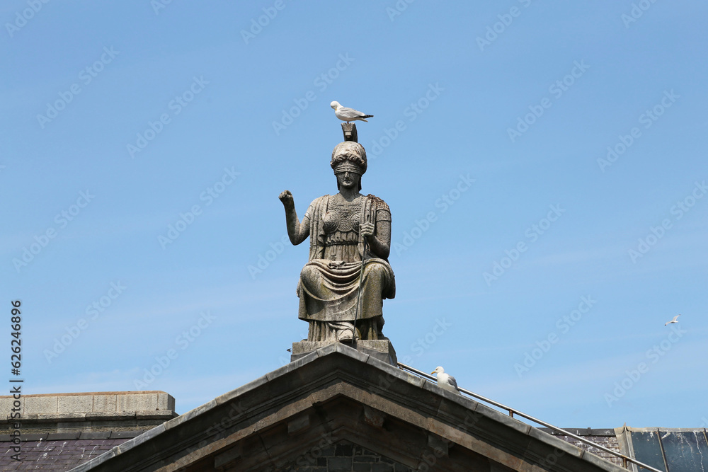 Obraz premium The Lady Justice statue on top of a roof in Gwynedd, Wales, UK.