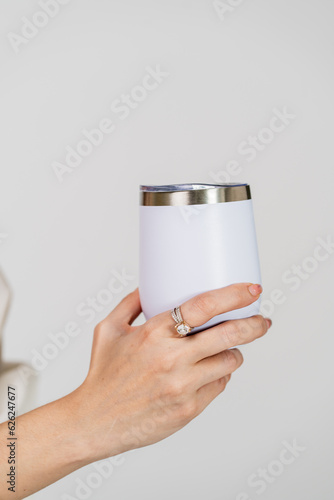 The mockup image showcases a woman in a white blank tumbler, striking a simple pose at an indoor studio, adding sophistication to your designs
