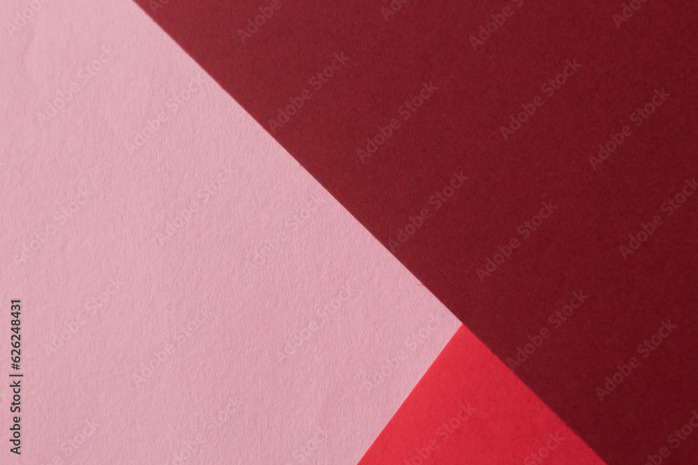 Paper in three shades of red lies on the table, creating a geometric composition Paper in three shades of red lies on the table, creating a geometric composition