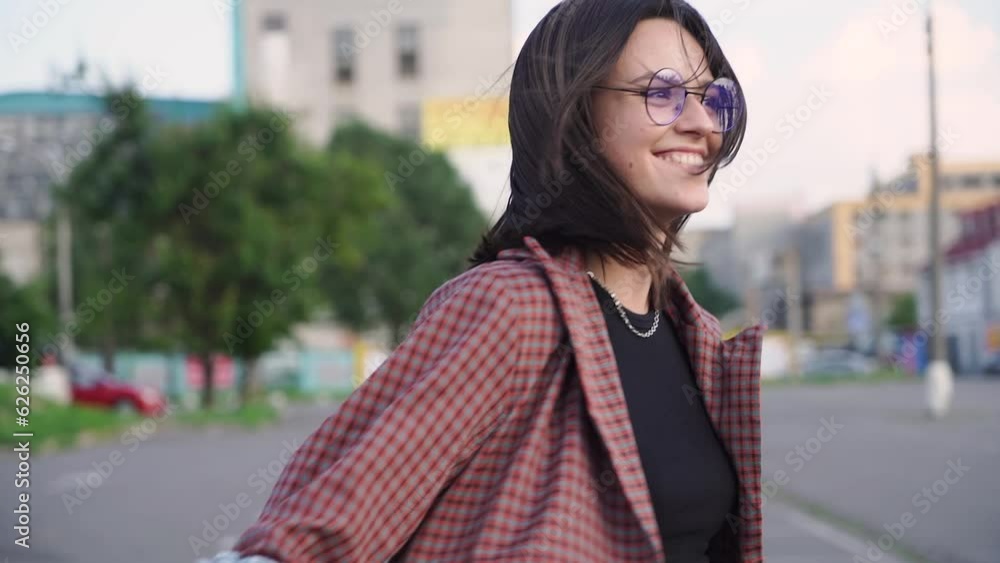 A young happy brunette woman twirling and smiling against a cityscape. Slow motion. A young happy brunette woman twirling and smiling against a cityscape. Slow motion.
