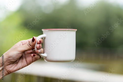 The mockup image showcases a woman in a white blank mug, striking a simple pose while presenting it, adding sophistication to your designs