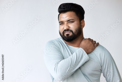 South asian Indian man suffering from shoulder pain, shoulder injury, shoulder stiffness symptoms with office syndrome