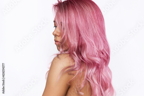 Young cacusian tanned woman with long toned wavy pink hair isolated on a white background. The result of coloring, highlighting, perming. Bright saturated extravagant color. Beauty and fashion concept