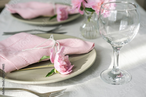 Table setting with light green ceramic plates and pink peonies